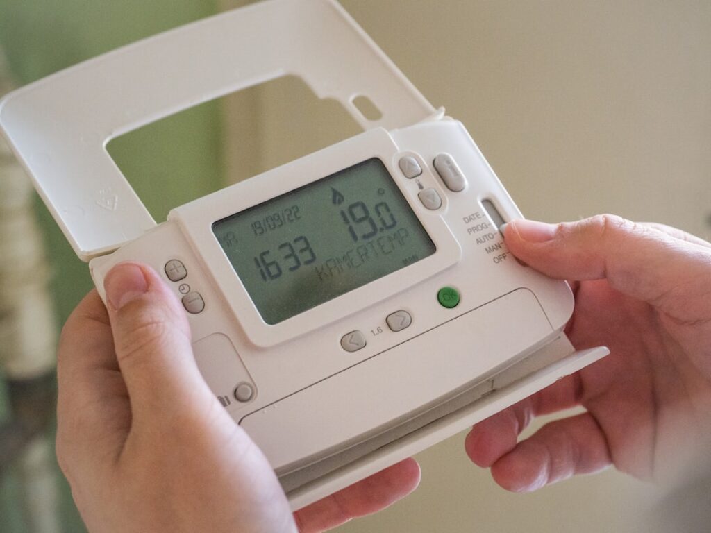 A person checking the filter of a home air conditioning vent in a bright, lived-in living room.