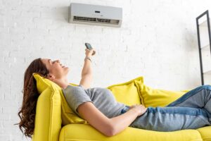 A person adjusting the settings on a digital wall-mounted home thermostat in a living room.