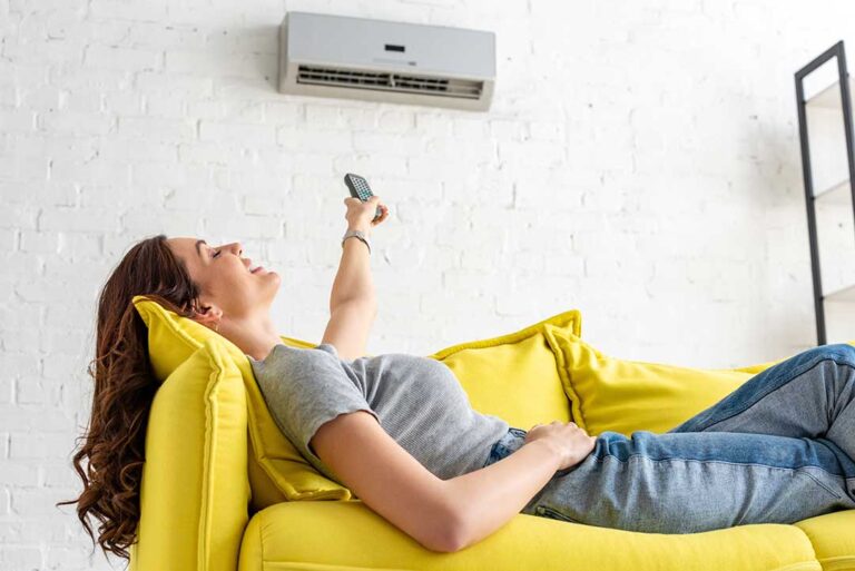 A person adjusting the settings on a digital wall-mounted home thermostat in a living room.