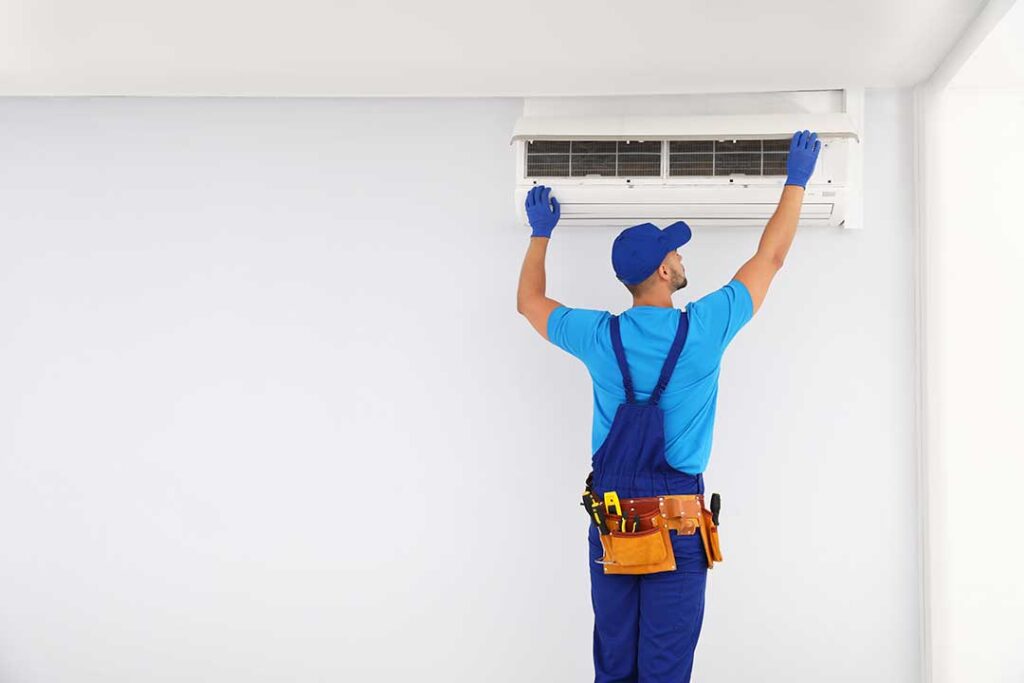 A homeowner adjusting a smart thermostat mounted on a hallway wall.