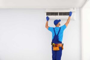 A homeowner adjusting a smart thermostat mounted on a hallway wall.