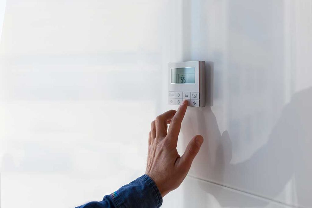 A person changing a pleated filter in a residential furnace or air handler closet.