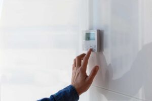 A person changing a pleated filter in a residential furnace or air handler closet.